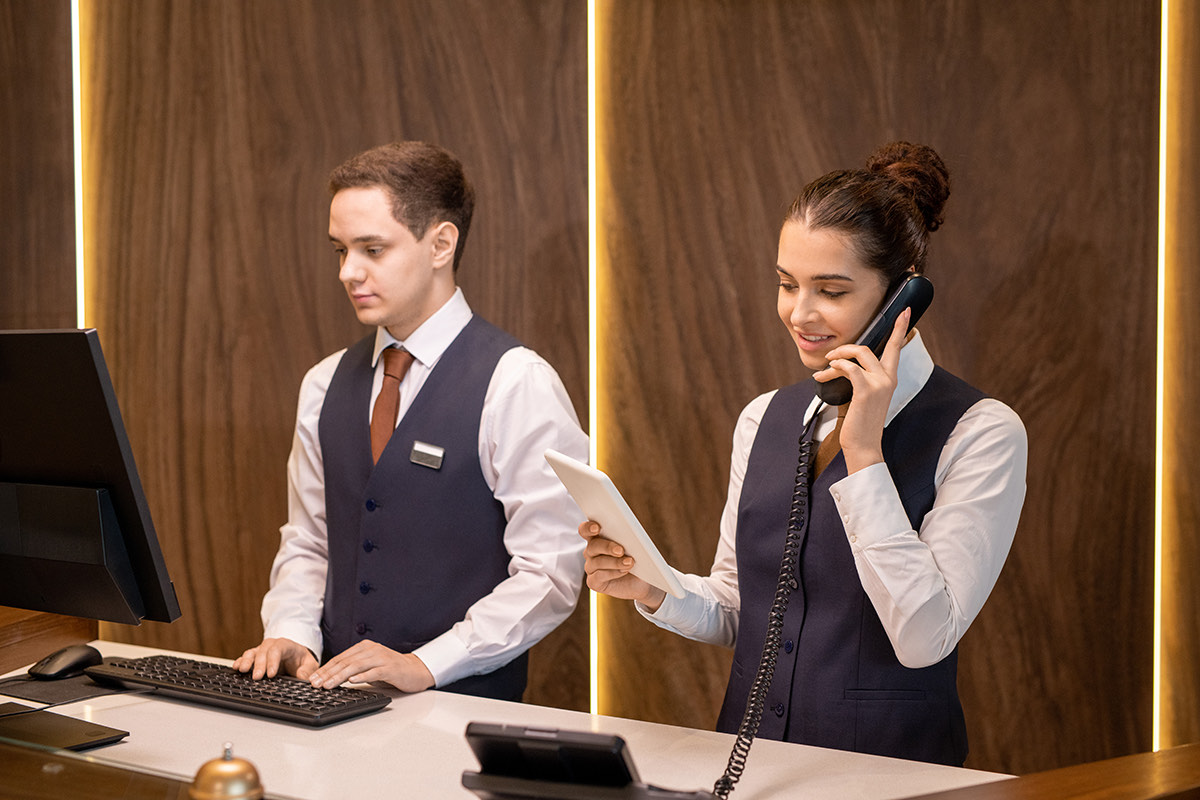 Recepcionistas de hotel atendiendo una llamada con teléfono IP y tablet